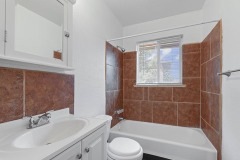 A bathroom with a white tub, sink, and toilet.