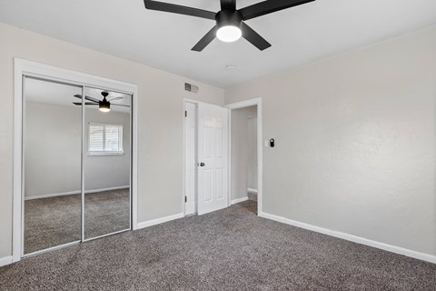 A room with a ceiling fan and a sliding glass door.