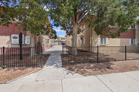 A tree-lined sidewalk in front of a brick building.