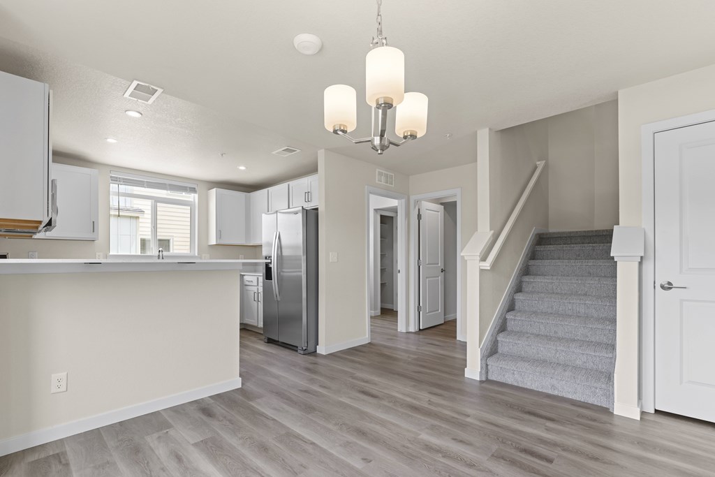 Kitchen with a refrigerator, stairs, and a chandelier at The Townhomes at Pine Drive, Parker, CO, Colorado, 80138