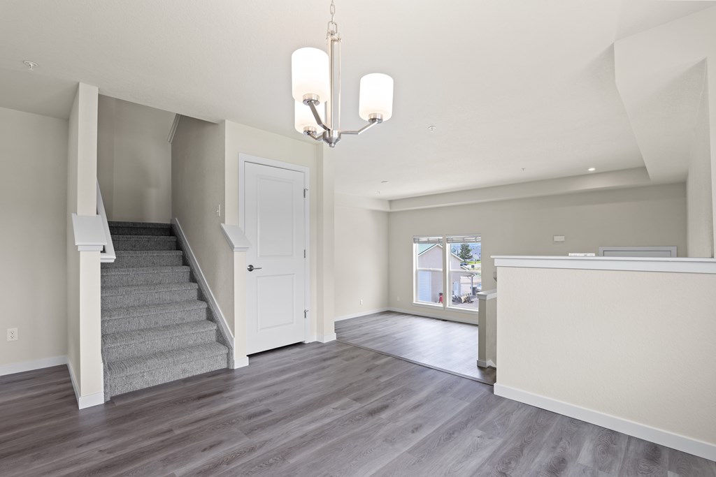 Large, empty room with a staircase and a chandelier at The Townhomes at Pine Drive, Parker, CO