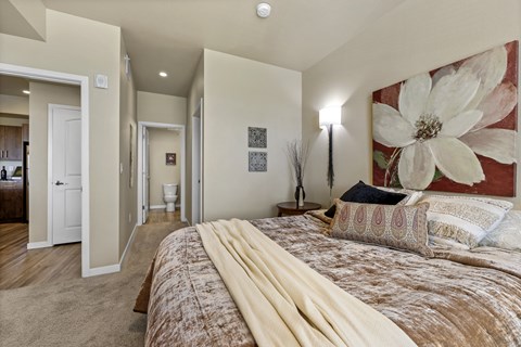 A bedroom with a large bed and a painting on the wall.