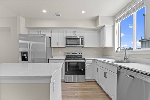 A modern kitchen with white cabinets and stainless steel appliances.