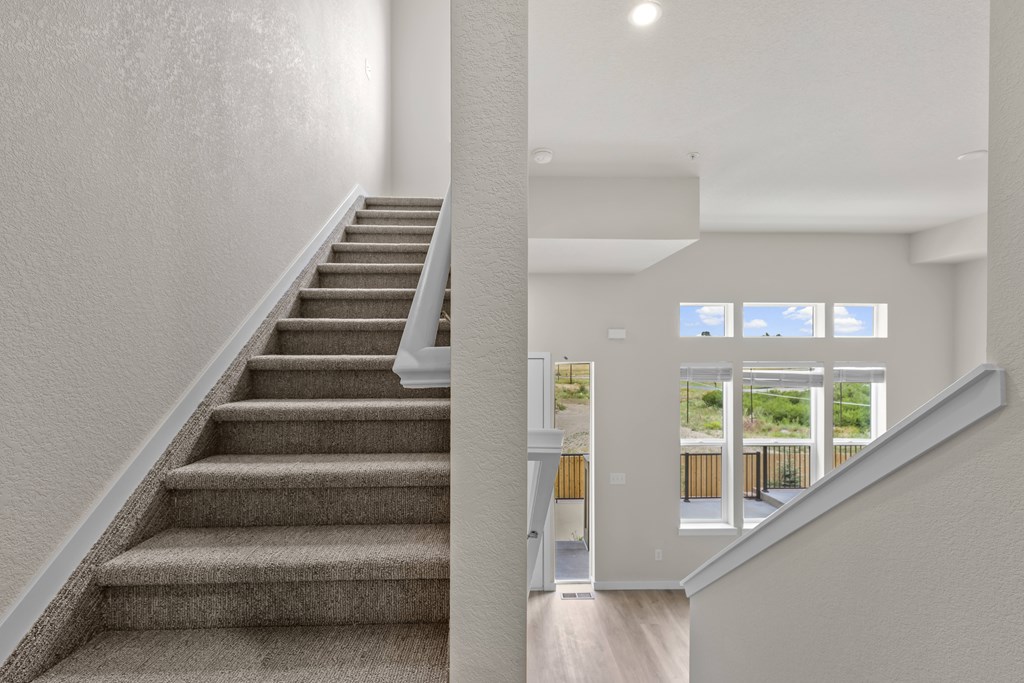 Staircase with a carpeted runner and a wooden handrail at The Townhomes at Pine Drive, Parker, CO, Colorado