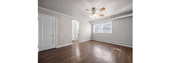 A room with a ceiling fan and wooden floors.