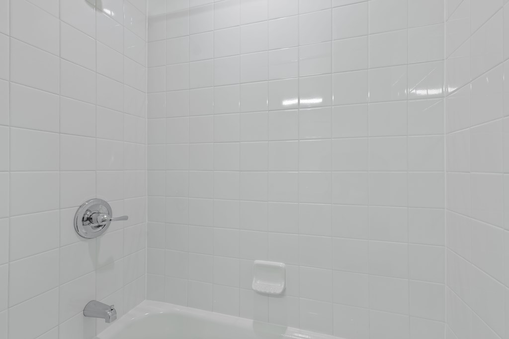White tiled bathroom with a white tub and faucet at The Townhomes at Pine Drive, Parker