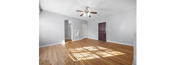 A room with a ceiling fan and wooden floors.