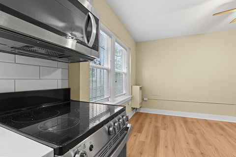 A modern kitchen with a stainless steel oven and wooden flooring.
