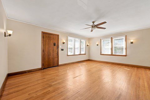 A room with a ceiling fan and wooden floors.