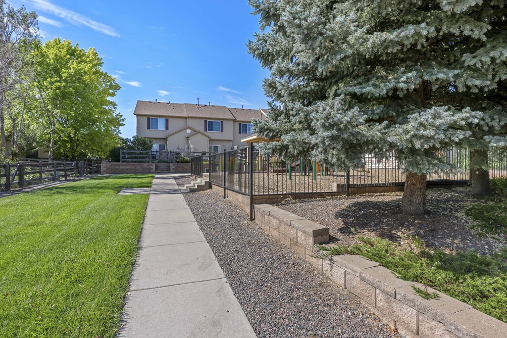 A house with a fence and a tree in front of it.