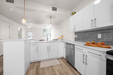 A modern kitchen with white cabinets and a wooden floor.