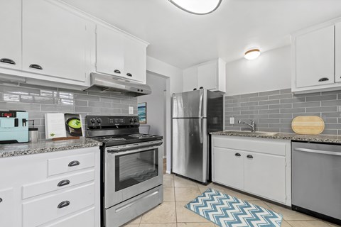A kitchen with a black stove top oven and a silver refrigerator.