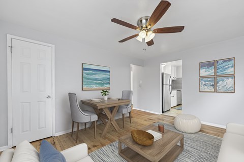 A living room with a ceiling fan and a dining table with chairs.