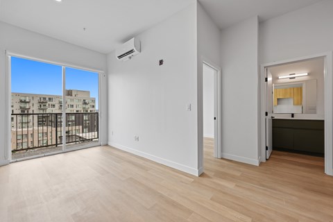 A spacious room with a sliding glass door leading to a balcony.