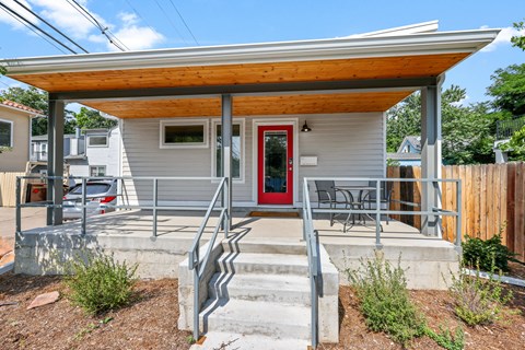 A small house with a red door and a wooden porch.