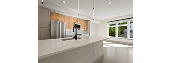 A modern kitchen with a white countertop and stainless steel appliances.