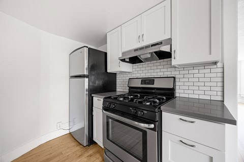A kitchen with a black stove top oven and white cabinets.