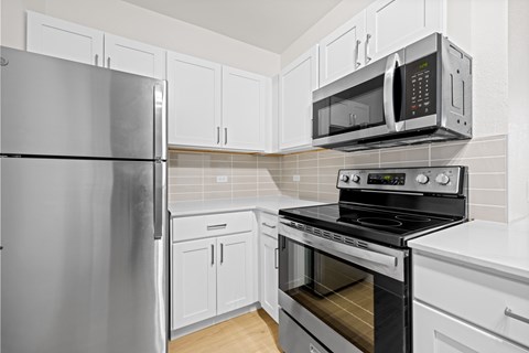 A kitchen with a refrigerator, microwave, oven and cabinets.