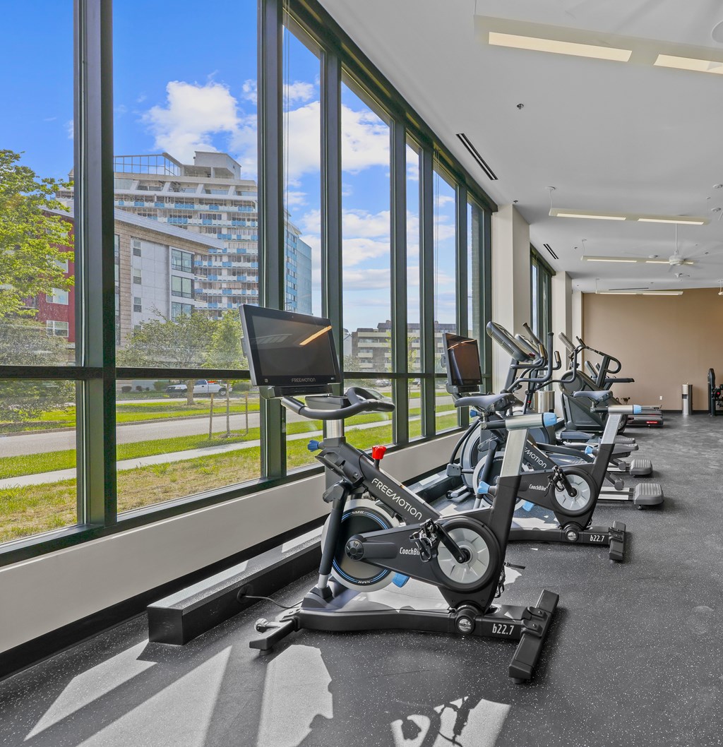 A gym with stationary bikes and a view of the outside.