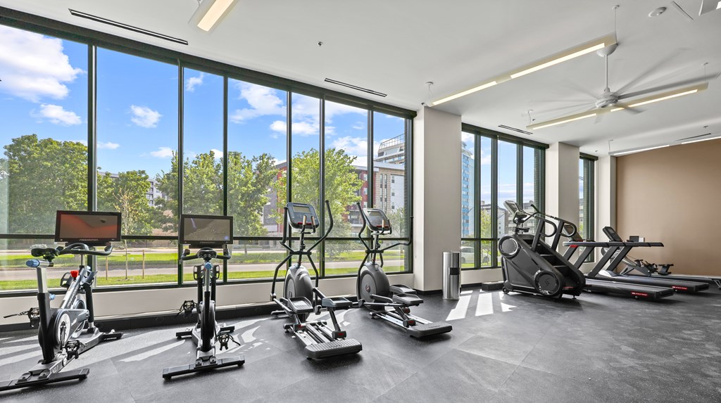 A gym with a row of exercise bikes and a fan.