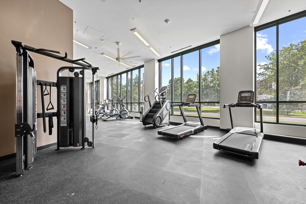A gym with treadmilers, elliptical machines, and a weight machine.
