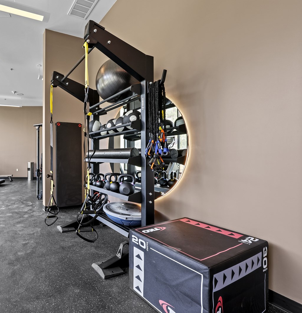 A gym with a weight rack, a box, and a mirror.