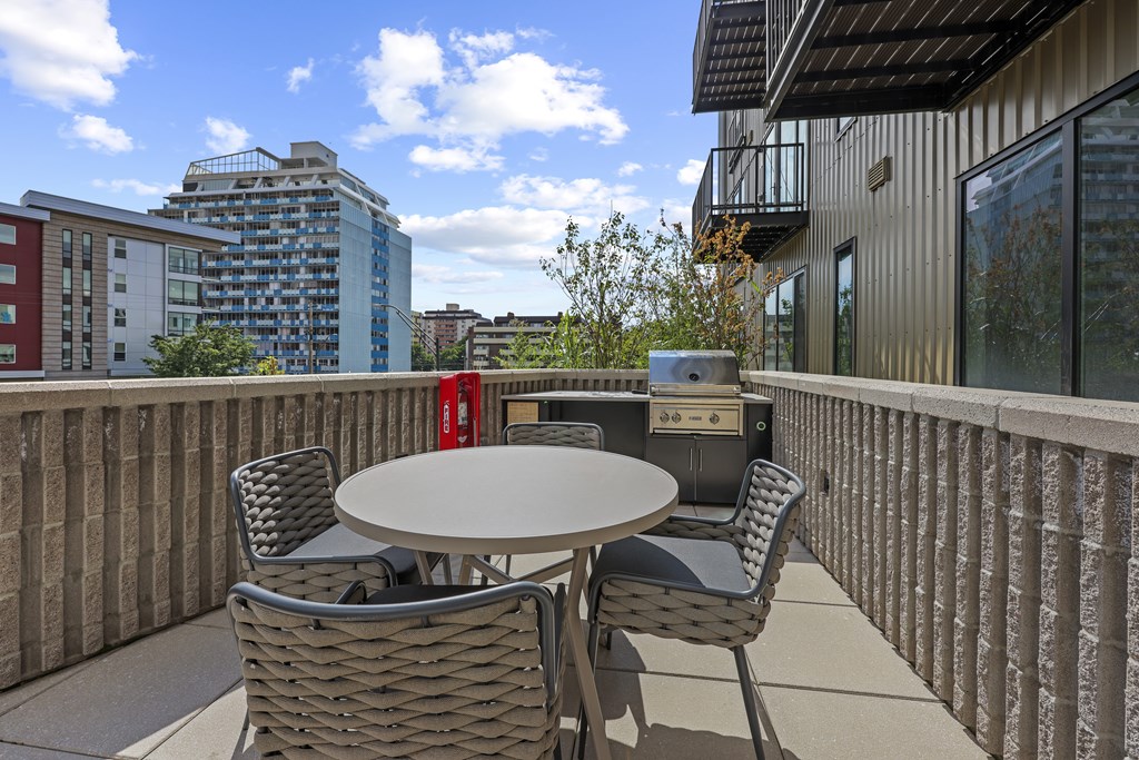 A patio with a table and chairs overlooking a cityscape.