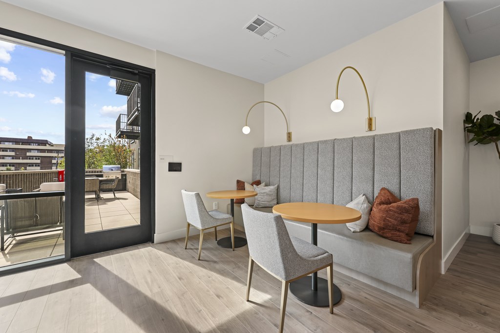A modern dining area with a table set for two and a view of the outdoors.