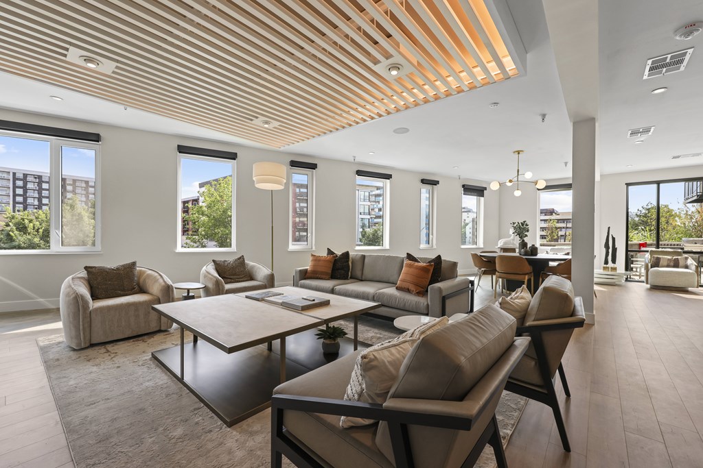 A modern living room with a wooden ceiling and a large table surrounded by chairs.