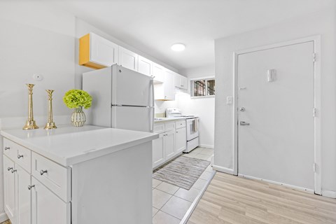 A kitchen with white cabinets and a white island.
