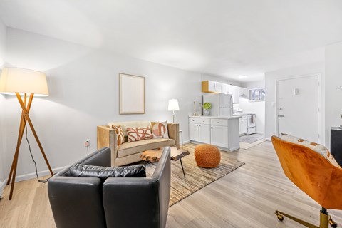 A living room with a black leather sofa and a wooden floor.