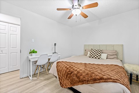 A bedroom with a bed, desk, and chair.