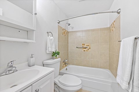 A white bathroom with a toilet, sink, and bathtub.