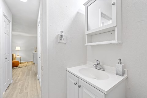 A white bathroom with a sink and mirror.