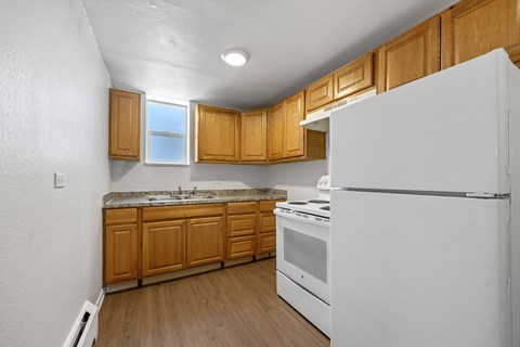 A white refrigerator in a kitchen with wooden cabinets.