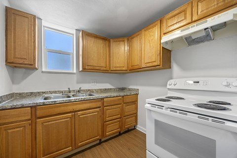 A kitchen with wooden cabinets and a white stove.
