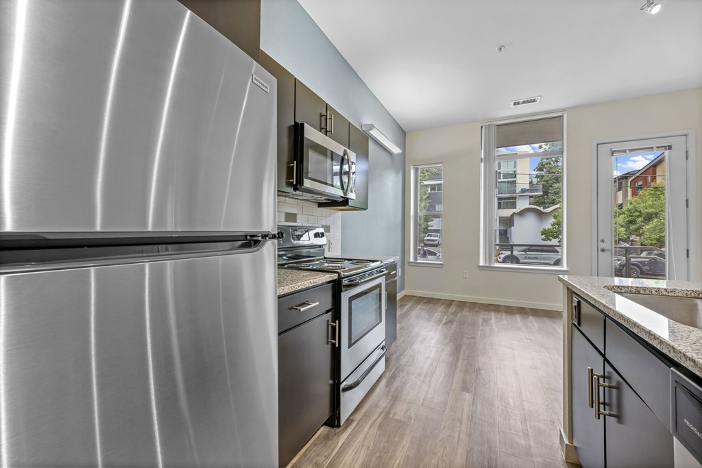 A modern kitchen with a stainless steel refrigerator and black appliances. at B Street Lohi Apartments, Colorado