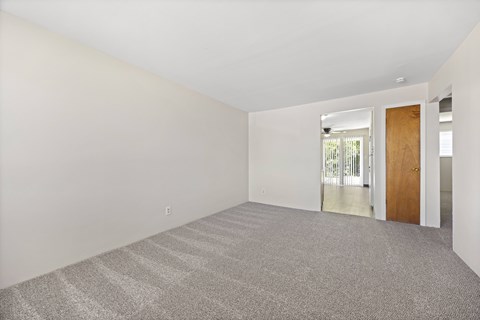 A room with a carpeted floor and a door leading to a balcony.