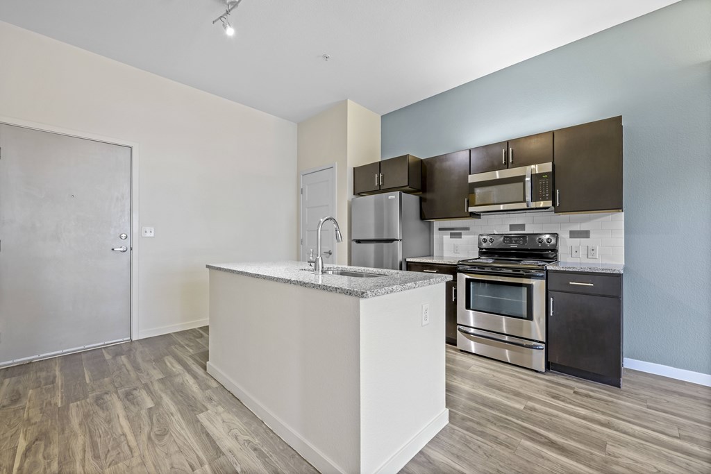 A kitchen with a white island and stainless steel appliances. at B Street Lohi Apartments, Denver, Colorado