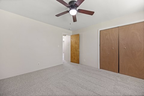 A room with a ceiling fan and carpeted floor.