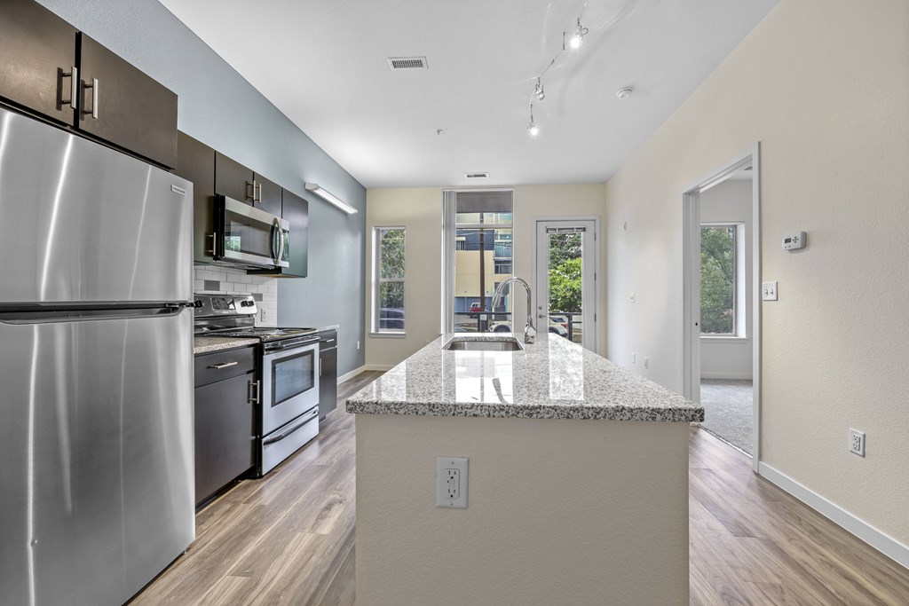 A kitchen with a granite countertop and stainless steel appliances. at B Street Lohi Apartments, Colorado