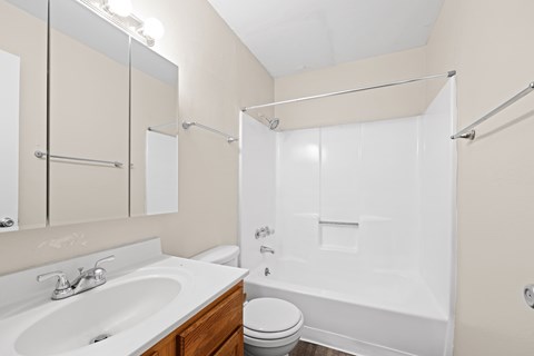 A white bathroom with a toilet, sink, and shower.