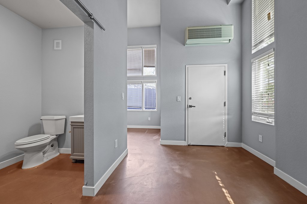 A bathroom with a toilet, sink, and window.