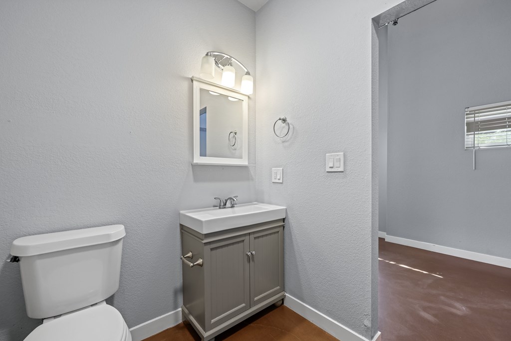A bathroom with a toilet, sink, and mirror.