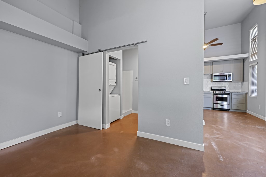 A room with a brown floor and a white wall with a door open.