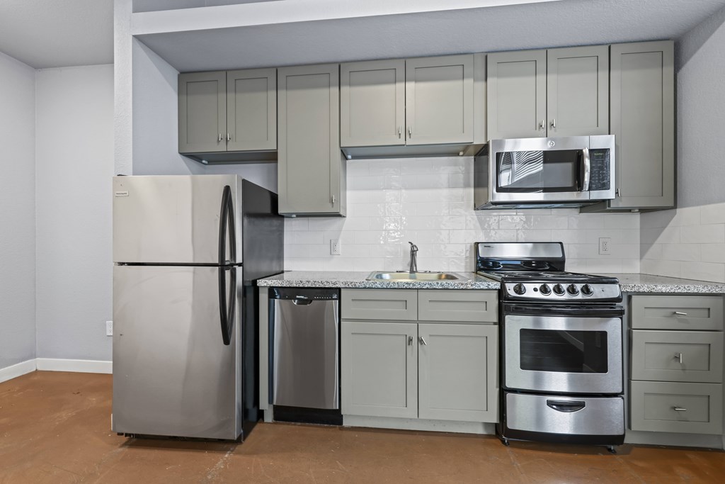 A kitchen with a refrigerator, oven, and microwave.