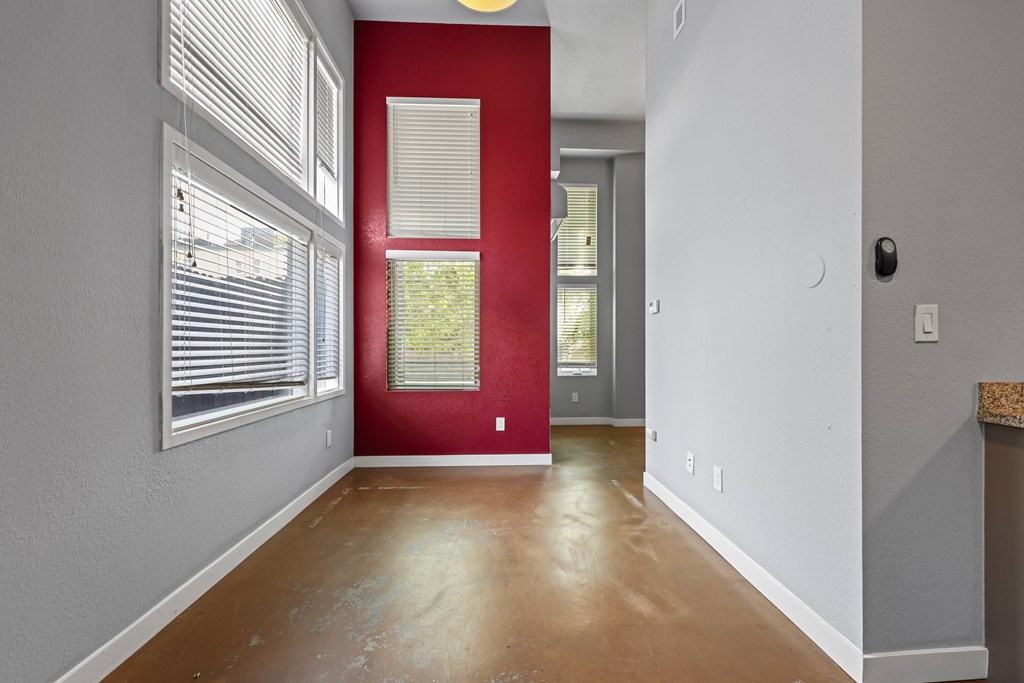 A room with a red door and a window with blinds.