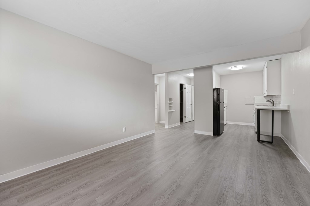 A spacious room with a kitchenette and a refrigerator.