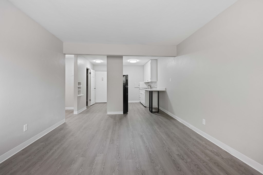 A long, empty hallway with a kitchen area at the end.