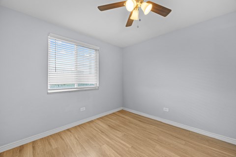 A room with a ceiling fan and a window with blinds.